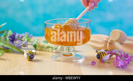Raw Wabe mit flüssigem Honig im Glas Glas mit Lavendel auf blauem Hintergrund. Stockfoto