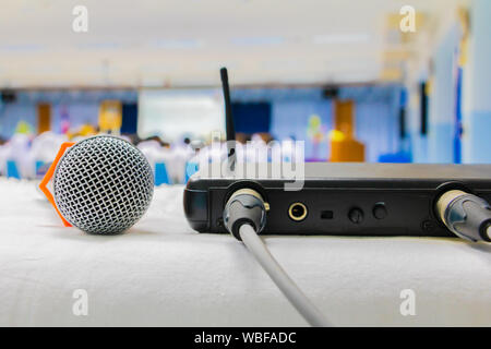 Nahaufnahme alten Mikrofon wireless mit Box Signal am weißen Tisch in Business Konferenz innen Seminar Tagungsraum und unscharfen Hintergrund Stockfoto