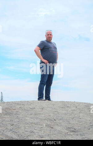 Vierzig Jahre alten Mann etwas hoch auf einem Hügel mit den blauen Himmel und Wolken im Hintergrund Stockfoto