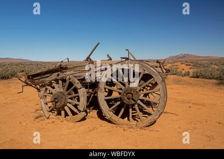 Alte Pferdekutschen farm Wagen in abgelegenen und trockenen Outback Landschaft mit roter Erde und niedriger Vegetation auf Ebenen unter blauem Himmel in Südaustralien abgebrochen Stockfoto