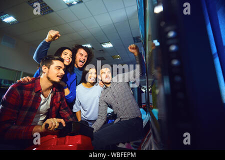 Eine Gruppe von Freunden, die Arcade Machine. Stockfoto