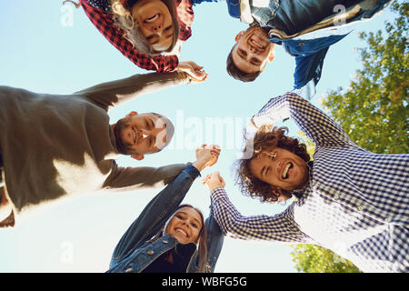 Aufgeregt Freunde im Kreis unter blauen Himmel Stockfoto