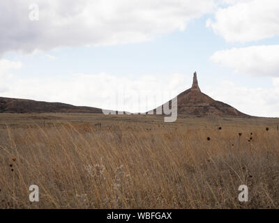 Chimney Rock National Historic Site in Nebraska mit Feld mit getrockneten Vegetation im Vordergrund. Bewölktem Himmel oben. Stockfoto