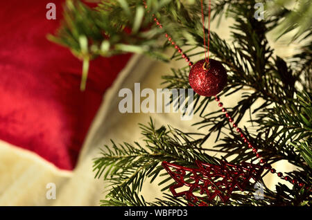 Weihnachtsschmuck und ein rotes, flauschiges Kissen Stockfoto