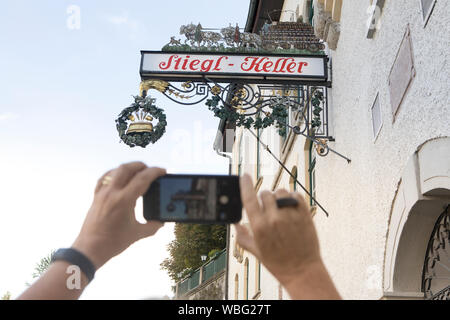 Salzburg, Austria-September 24,2017: Tourist nimmt ein Foto der schmiedeeisernen Zeichen einer Brauerei namens Stiegl Keller in der Stadt Salzburg Stockfoto