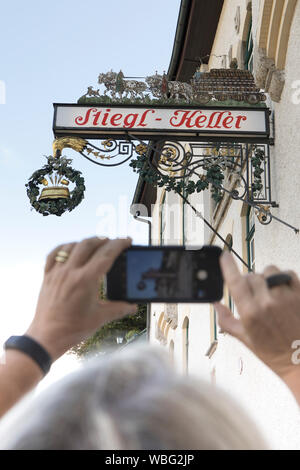 Salzburg, Austria-September 24,2017: Tourist nimmt ein Foto der schmiedeeisernen Zeichen einer Brauerei namens Stiegl Keller in der Stadt Salzburg Stockfoto