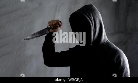 Gefährlich mit Kapuze Mann im Dunkeln und halten ein Messer Gesicht nicht gesehen werden kann. Stockfoto