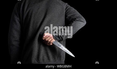 Die Banditen im Schwarzen halten Sie ein Messer hinter auf schwarzem Hintergrund ausgeblendet. mit Freistellungspfaden. Stockfoto