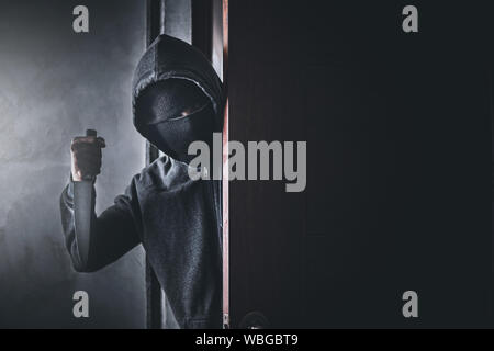 Der Dieb hält ein Messer die Haustür für Raub zu öffnen. Stockfoto