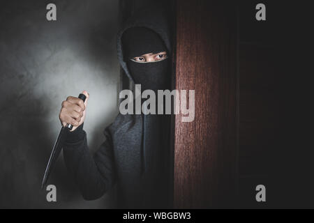 Der Dieb hält ein Messer die Haustür für Raub zu öffnen. Stockfoto
