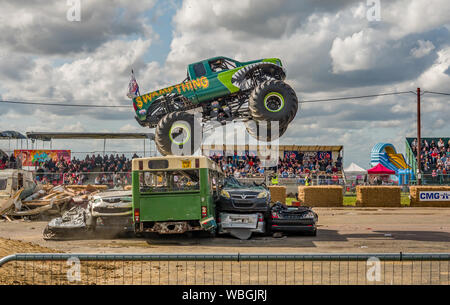 Die Monster truck Sumpf Sache Sprung über einen ausgedienten Bus während der Demonstration zu einem Monster Truck Show in Santa Pod raceway Stockfoto