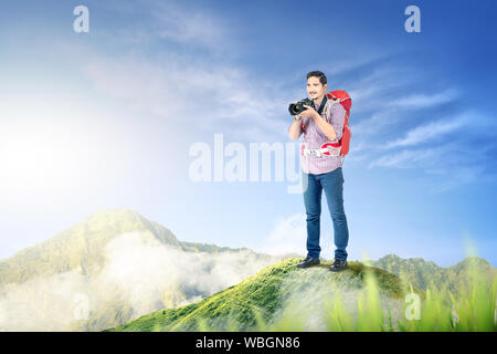 Asiatischer Mann mit einem Rucksack mit einer Kamera Bilder auf der Oberseite des Green Mountain zu nehmen Stockfoto