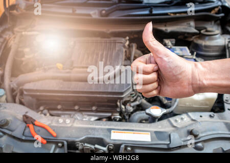 Automechaniker zeigen einen Daumen nach oben, nachdem das Auto, Überprüfung und Reparatur in der Werkstatt. Stockfoto