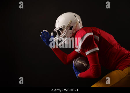 Foto der laufenden sportlerin mit rugby ball, Helm auf leeren schwarzen Hintergrund Stockfoto