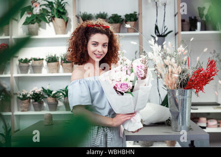Fröhliche junge Dame mit roten Brille auf dem Kopf ihr Blumen angezeigt Stockfoto