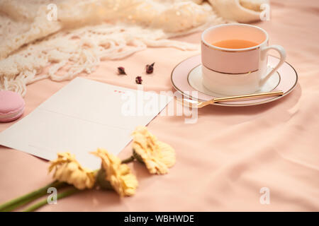 Umschlag, Blumen, und macarons mit Tasse Tee auf hellen Hintergrund Stockfoto