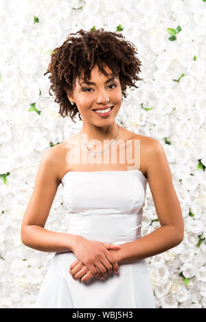 Fröhlich afrikanische amerikanische Braut auf Kamera beim Stehen in der Nähe von Blumen Stockfoto