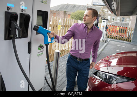 Ryan Todd, Inhaber der sieben Elektromotor Autos läuft als Taxi's in seinem Geschäft Todd Taxen, Gebühren sein Auto an der Princes Street elektrische Ladestation, einer von drei solche Stationen in der Stadt, in Dundee, Schottland, am 14. August 2019. Stockfoto