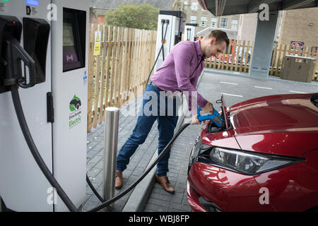 Ryan Todd, Inhaber der sieben Elektromotor Autos läuft als Taxi's in seinem Geschäft Todd Taxen, Gebühren sein Auto an der Princes Street elektrische Ladestation, einer von drei solche Stationen in der Stadt, in Dundee, Schottland, am 14. August 2019. Stockfoto