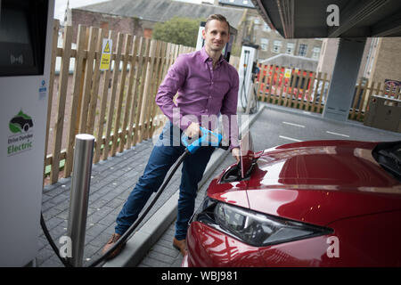 Ryan Todd, Inhaber der sieben Elektromotor Autos läuft als Taxi's in seinem Geschäft Todd Taxen, Gebühren sein Auto an der Princes Street elektrische Ladestation, einer von drei solche Stationen in der Stadt, in Dundee, Schottland, am 14. August 2019. Stockfoto