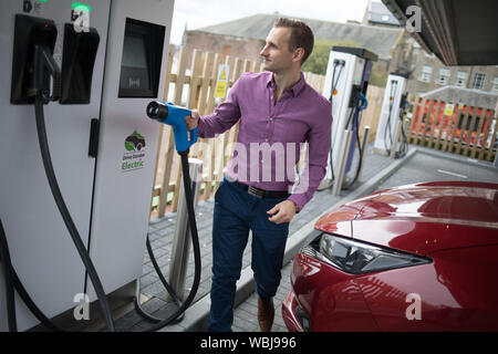 Ryan Todd, Inhaber der sieben Elektromotor Autos läuft als Taxi's in seinem Geschäft Todd Taxen, Gebühren sein Auto an der Princes Street elektrische Ladestation, einer von drei solche Stationen in der Stadt, in Dundee, Schottland, am 14. August 2019. Stockfoto