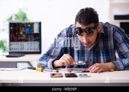 Die junge schöne Techniker Reparatur Handy Stockfoto
