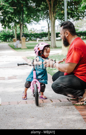 Junger Vater verbringen Zeit mit niedlichen kleinen asiatischen 2 Jahre altes Kleinkind Mädchen Kind, Vater und Kind Spaß mit balance Bike (Fahrrad) auf Natur, Papa te Stockfoto