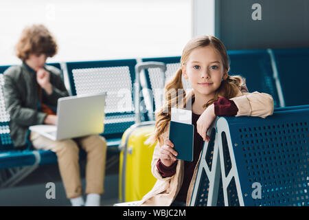 Selektiver Fokus auf Jugendliche kid Holding Passport und sitzen auf Blau Sitz in Wartehalle Stockfoto