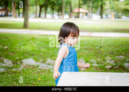 Asiatische 1 Jahr altes Kleinkind besetzt ist, spielen in einem tropischen Park am Morgen. Stockfoto