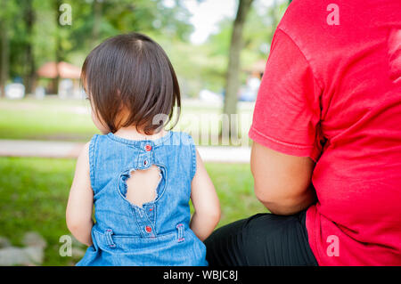 Zurück Vater und Tochter genießen Sie Blick auf den Park in einem tropischen Park, auf einer Bank sitzen. Kinder und Papa zusammen Outdoor. Stockfoto