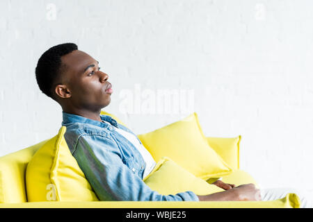 Seitenansicht der Ruhe der afrikanischen amerikanischen Mann auf der Couch zu Hause sitzen Stockfoto