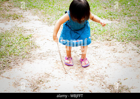 Asiatische 1 Jahr altes Kleinkind besetzt ist, spielen in einem tropischen Park am Morgen. Stockfoto