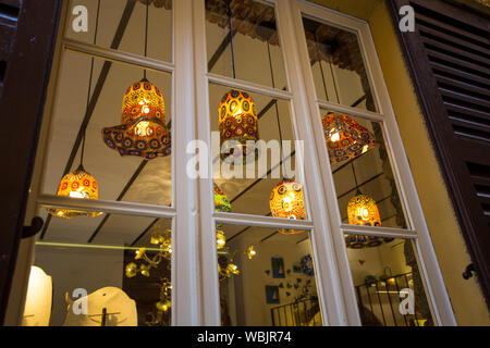 Kronleuchter aus Glas mit Lichtern geschmückt leuchtet durch das Fenster Stockfoto