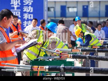 (190827) -- XIONGAN, Aug 27, 2019 (Xinhua) - Kandidaten Schneiden 10-kv-Strom Kabel während einer beruflichen Fähigkeiten Wettbewerb in Xiongan neue Bereich gehalten, im Norden der chinesischen Provinz Hebei, Aug 27., 2019. Dutzende von Mitarbeitern aus Peking, Tianjin und Hebei Provinz Teil in eine berufliche Qualifikation bestreiten, dass hier Dienstag trat, konkurrieren in Fliesen und Schneiden 10-kv-Stromleitungen. (Xinhua / Xing Guangli) Stockfoto