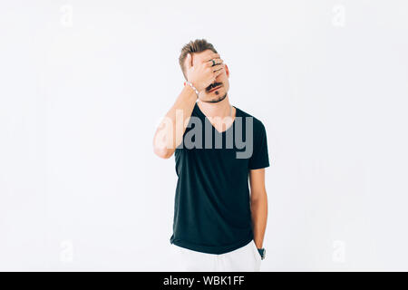 Enttäuscht junger Mann bedeckte sein Gesicht mit einem Palm auf weißem Hintergrund isoliert. Stockfoto