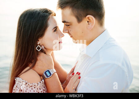 Nahaufnahme einer glücklichen kuscheln Paar bei Sonnenuntergang. Schöne Frau und gutaussehenden Mann in die Augen zu schauen. Stockfoto