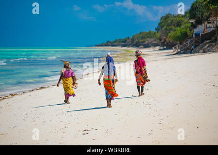 Zanzibar Beach muslimischen Frauen in nationalen helle Kleidung am Strand spazieren gehen Stockfoto