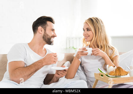 Schönes Paar mit Cups beim Frühstück im Bett am Morgen Stockfoto