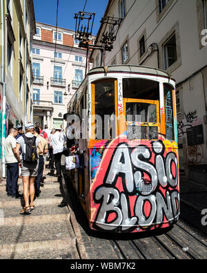 Touristen Aussteigen aus einem Graffiti bedeckt Standseilbahn Straßenbahn, Lissabon, Portugal. Stockfoto