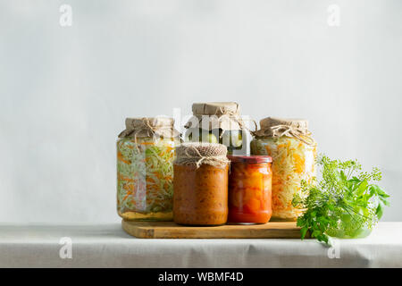 Fermentierte oder canning verschiedene Gemüse zucchini Möhren sauerkraut Gurken in Gläsern auf einem Tisch. Verarbeitung der Herbst Ernte. Natürlichen rustikalen Stil Stockfoto