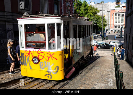 Touristische boarding ein Graffiti bedeckt Standseilbahn Straßenbahn, Lissabon, Portugal. Stockfoto