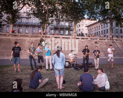 LYON, Frankreich - 18. JULI 2019: Band der Musiker Üben vor der Menschen sitzen am Ufer der Rhone (QUAIS) am Abend, während Mitarbeiter Stockfoto