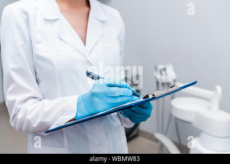 7/8-Ansicht von Zahnarzt schriftlich festhalten und Zwischenablage in Klinik Stockfoto