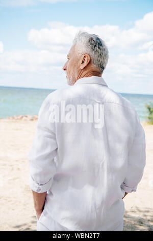 Rückansicht des älteren Mann im weißen Hemd am Strand im sonnigen Tag Stockfoto