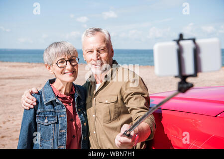 Lächelnd senior Paar umfassend und unter selfie im sonnigen Tag Stockfoto