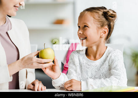 7/8-Ansicht der glücklichen Mutter, Tochter von Apple Stockfoto