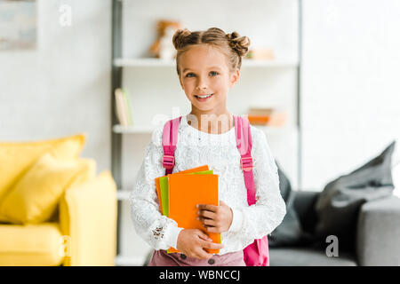 Glückliche Schülerin steht mit Rucksack und Holding Bücher Stockfoto