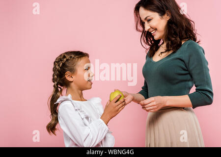 Glückliche Mutter, lecker Apple süße Tochter isoliert auf Rosa Stockfoto