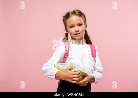 Glückliches Kind holding Lunch Box und lächelnd auf Rosa Stockfoto