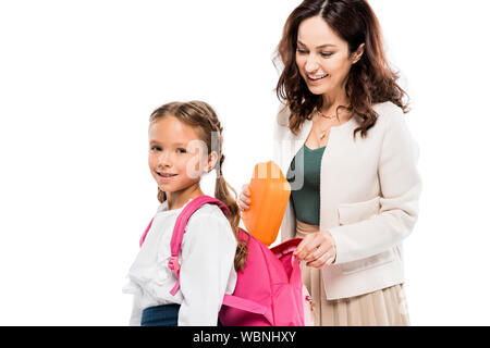 Attraktive Mutter, Lunch Box im Rucksack von niedlichen Tochter isoliert auf weißem Stockfoto